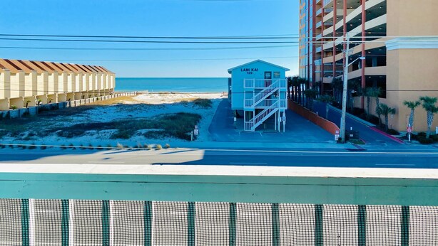 A beachside building with a name sign, a parking structure, and a clear view of the ocean. - Lani Kai Village 211, Beautifully Remodeled Condo with Indirect Gulf Views! (Gulf Shores)