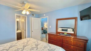 A bedroom with a bed, dresser, ceiling fan, and a TV on the wall. - Lani Kai Village 211, Beautifully Remodeled Condo with Indirect Gulf Views! (Gulf Shores)
