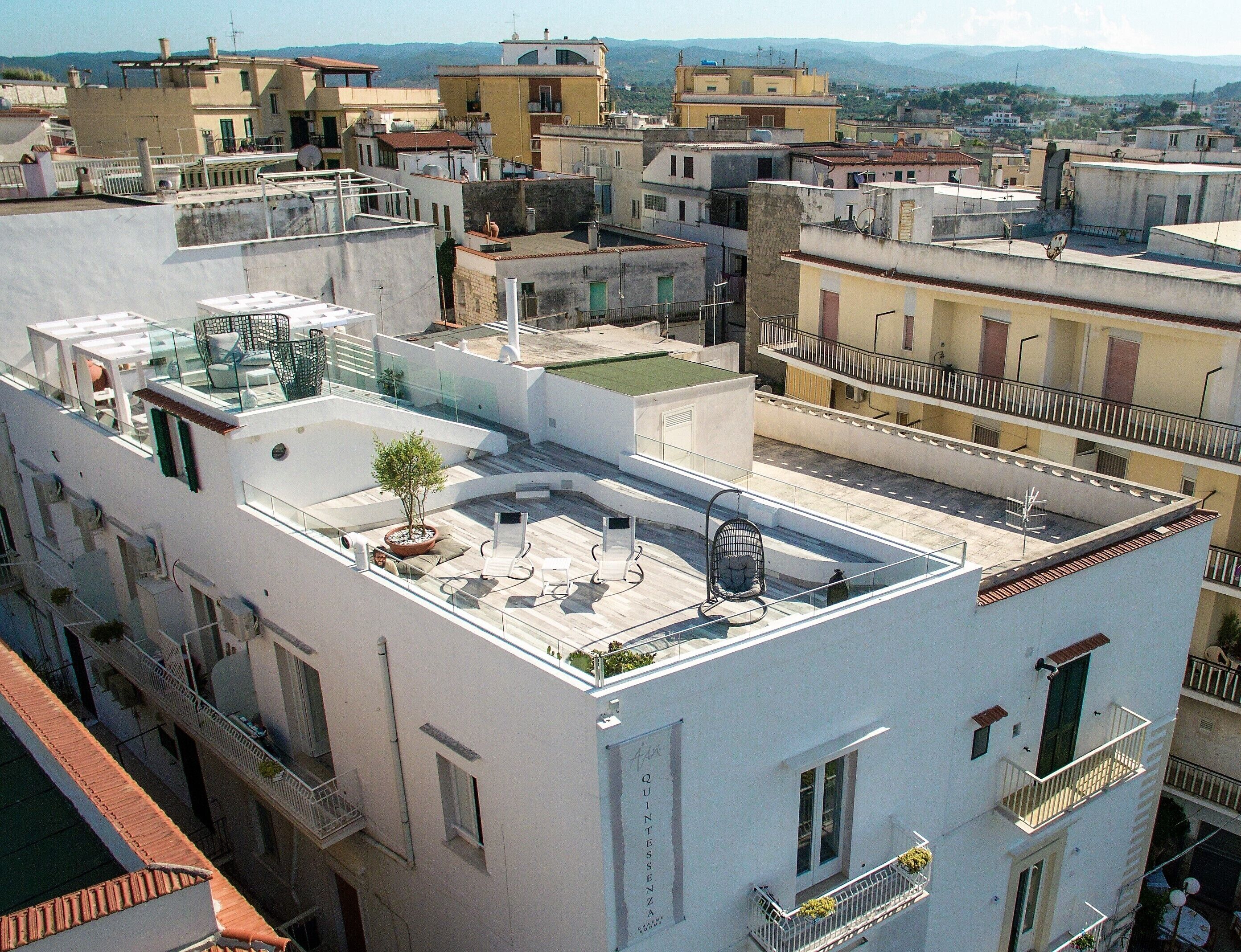 A rooftop terrace with a small tree, seating area, and a view of the surrounding buildings.