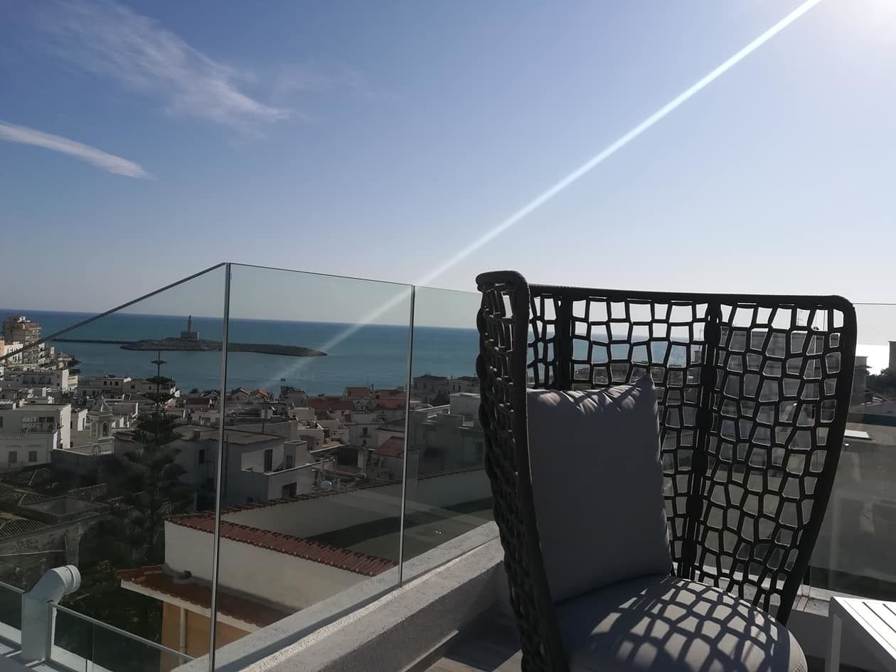 Uma varanda com vista ampla para o mar e prédios.