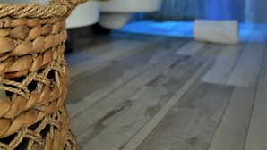 A bathroom with a wooden wall, a white bathtub, and a woven basket on the floor. - Quintessenza - Charme Rooms (Vieste)