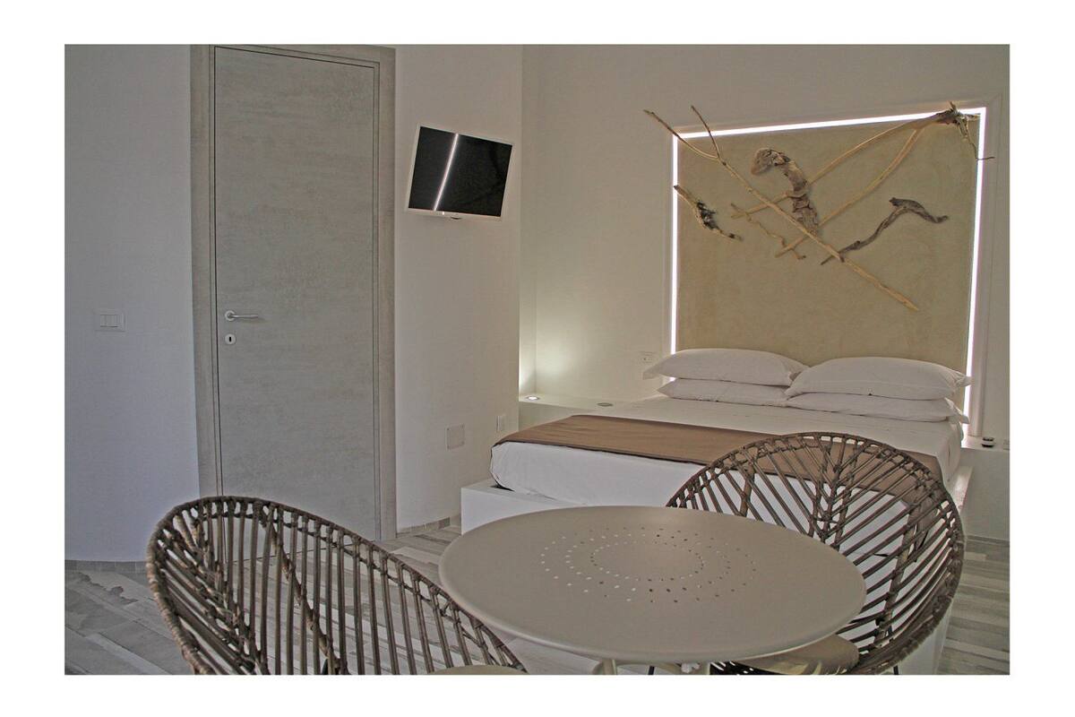 Une chambre à coucher avec un lit, une télévision, une chaise et une table.