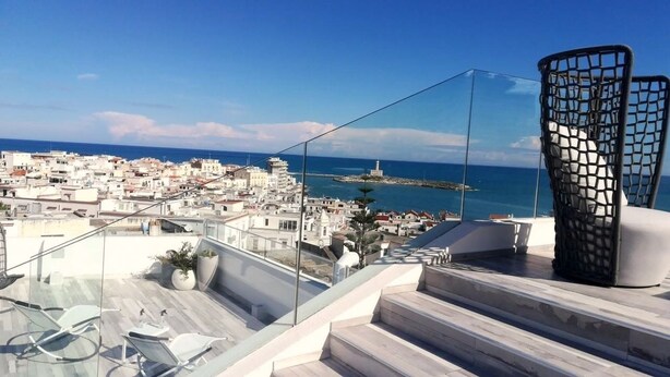 A rooftop terrace with a clear view of a coastal cityscape, including a lighthouse and a bridge. - Quintessenza - Charme Rooms (Vieste)