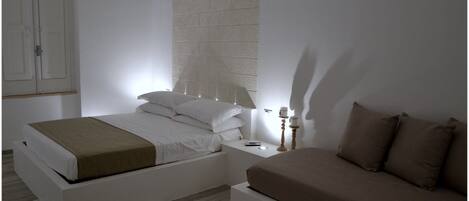 A minimalist bedroom with a bed, bedside table, lamp, and a nightstand.