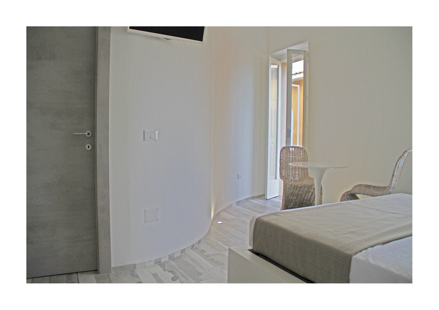 Un dormitorio con una cama, una silla y una puerta que da a un balcón.