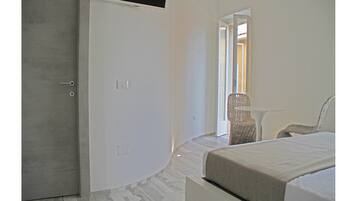 A bedroom with a bed, a chair, and a door leading to a balcony.