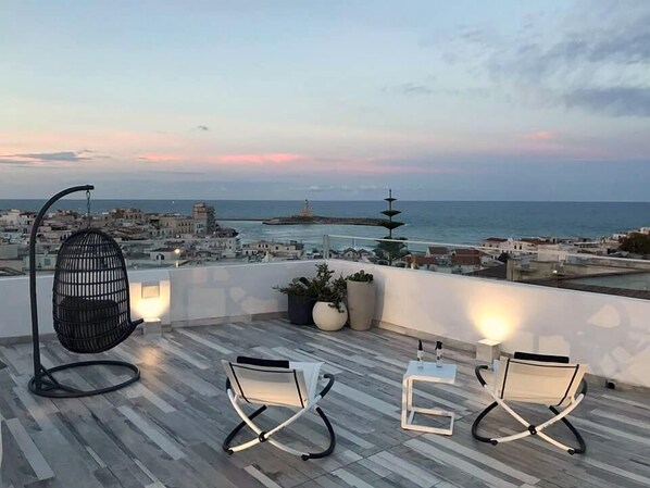 A rooftop terrace with two modern chairs, a hanging chair, and potted plants. - Quintessenza - Charme Rooms (Vieste)