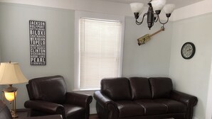 Una sala de estar con dos sofás de cuero, una mesa de centro de madera, una lámpara y un reloj de pared.