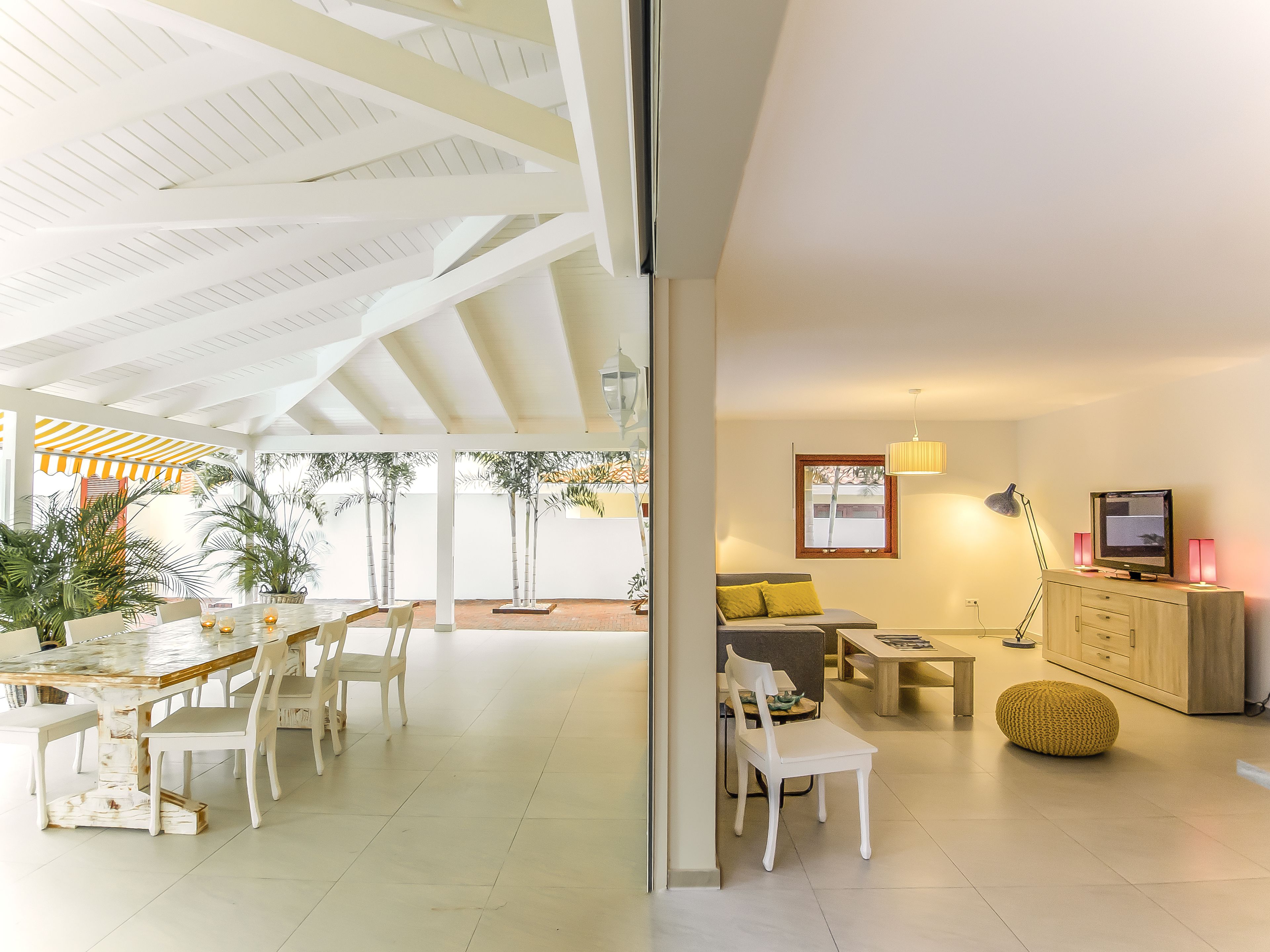 A spacious living area with a dining table, chairs, a sofa, a TV, and a cabinet.