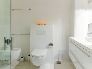A modern bathroom with a glass shower enclosure, a white toilet, and a vanity with a mirror.