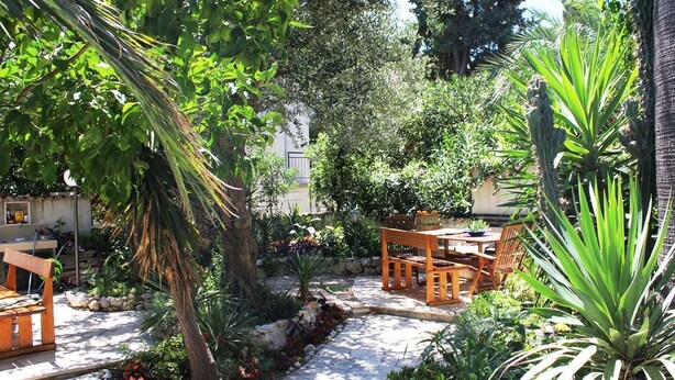 Eine Terrasse mit einem Kiesweg, Holzmöbeln und verschiedenen Pflanzen.