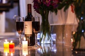 Una mesa con una botella de vino, dos copas de vino y tres velas.