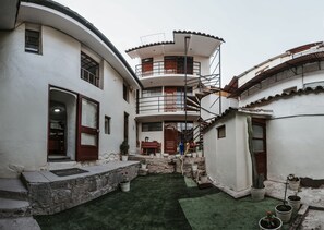 Un patio con escalera en espiral, plantas en macetas y un muro de piedra.