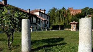 A building with a traditional architectural style, surrounded by a grassy area with two prominent stone pillars. - La Cascina del Castello (Asti)