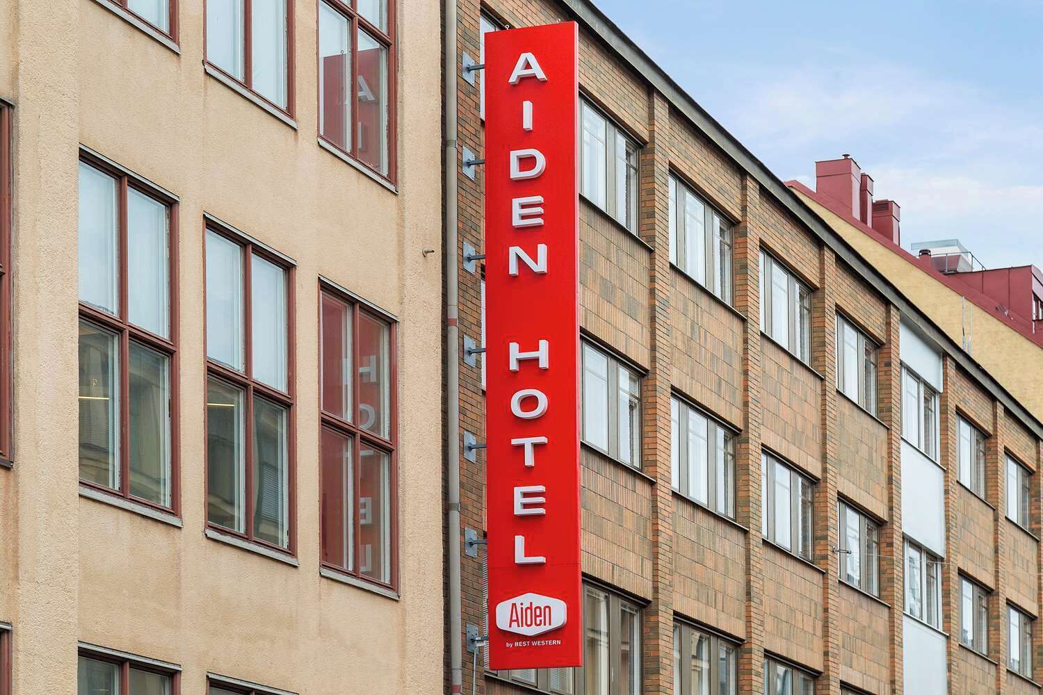Ein rotes, vertikales Schild für das Aiden Hotel, das angibt, dass es ein Bestandteil von Best Western ist.