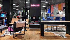 A modern indoor space with a neon sign, seating areas, and a gaming console. - Connect hotel city (Stockholm)