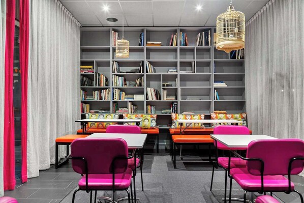 A library with bookshelves, tables, and chairs. - Connect hotel city (Stockholm)