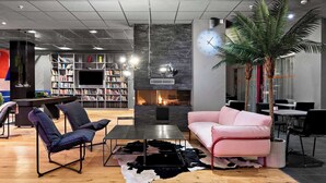 A modern living room with a fireplace, bookshelves, a coffee table, and a pink sofa. - Connect hotel city (Stockholm)
