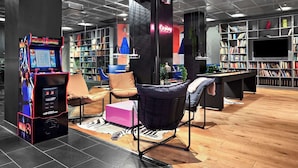 A modern library with a pool table, comfortable seating, and a large collection of bookshelves. - Connect hotel city (Stockholm)