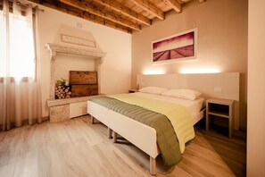 A bedroom with a bed, a bench, a fireplace, and a painting on the wall. - Casa Bassetto (Longare)