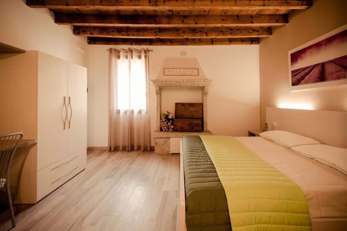 A bedroom with a bed, a fireplace, a wardrobe, and a chair.