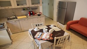 Een compacte keuken met een eettafel voor vier personen, een bank en een koelkast.