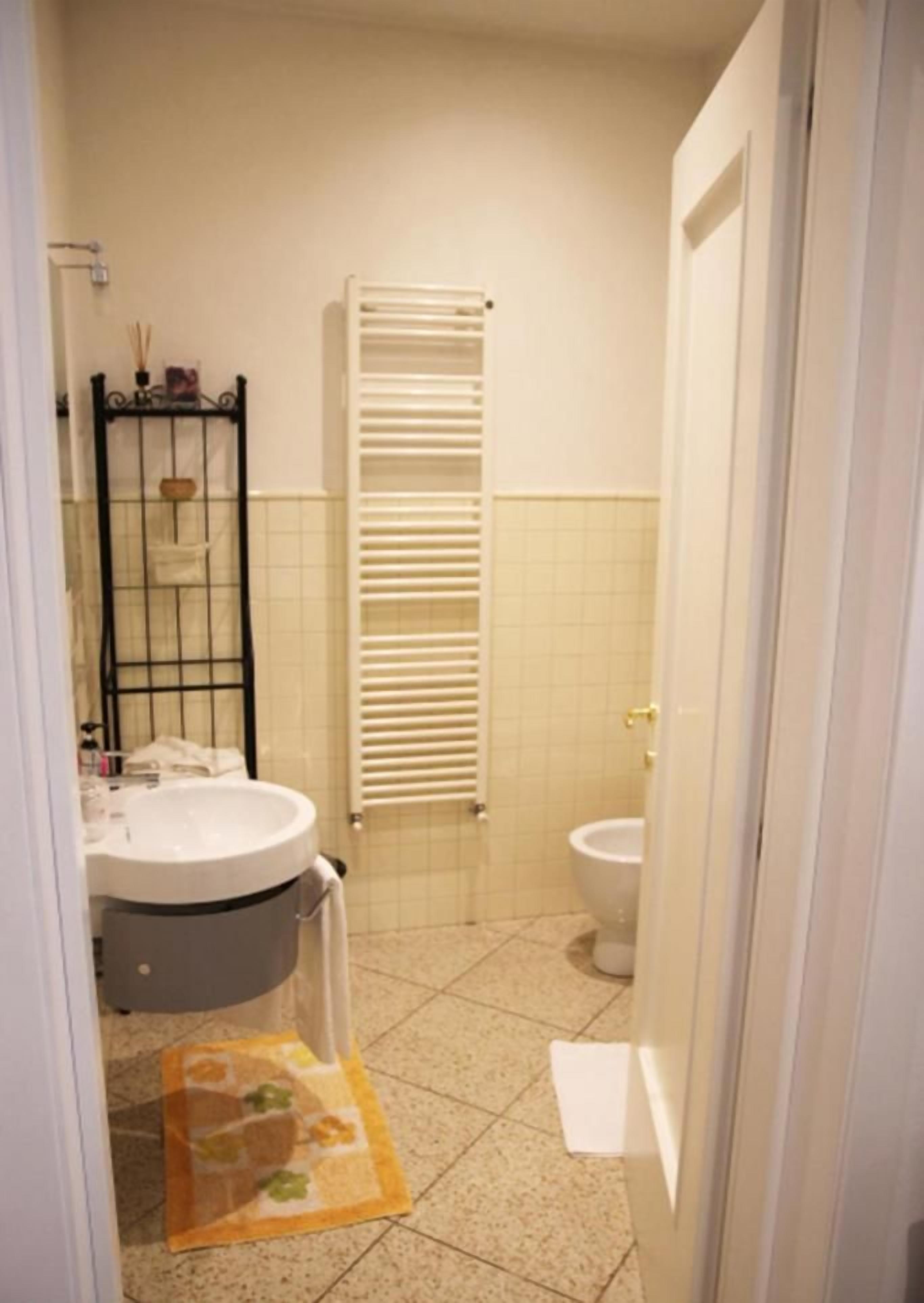 Un bagno con lavandino, WC, porta asciugamani e zona doccia.