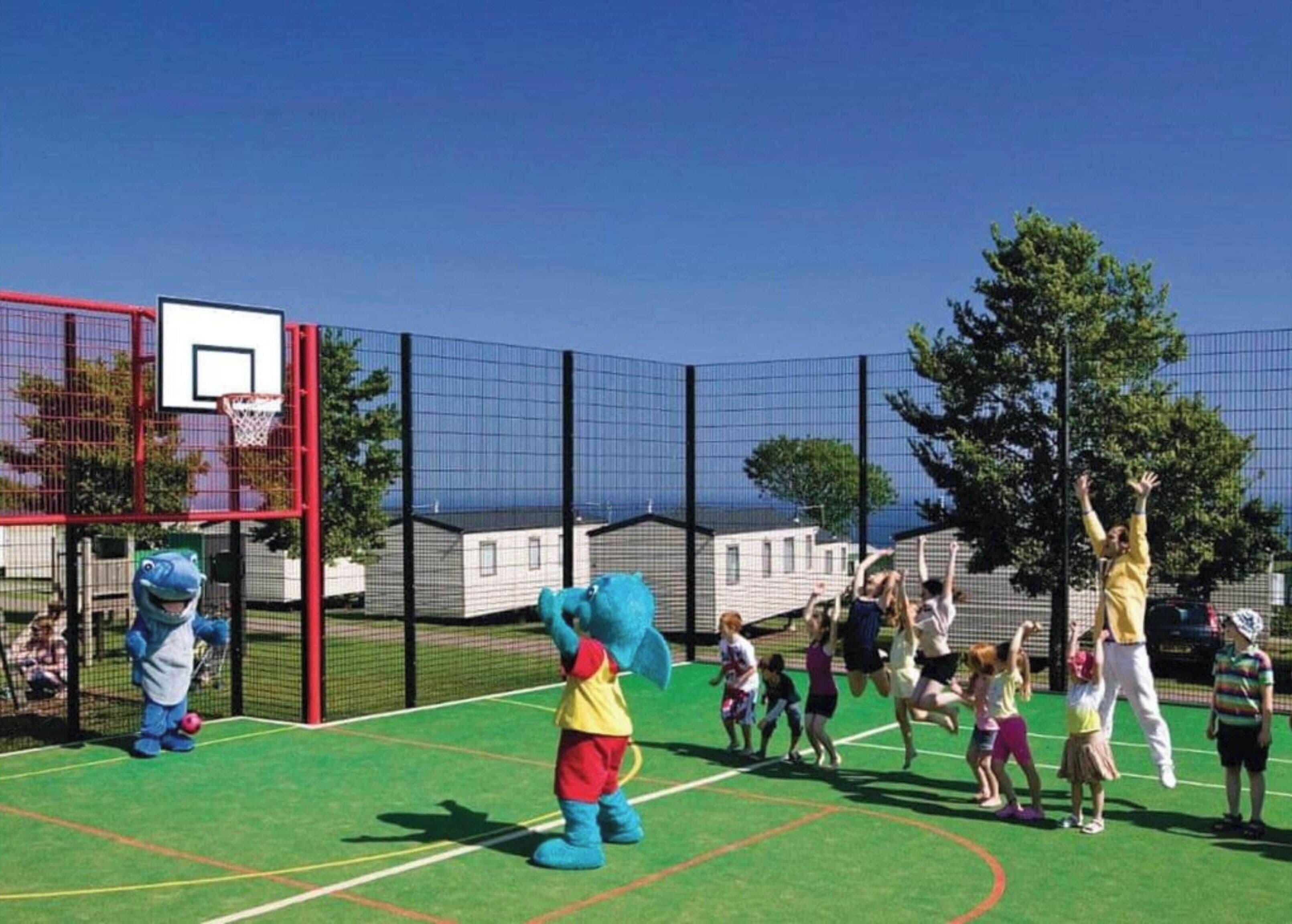 Un parc infantil amb un cèrcol de bàsquet i una mascota.