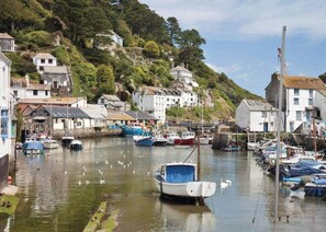 A harbor with boats, a small boat docked in the foreground, and buildings on a hillside in the background. - Tencreek Holiday Park (Looe)