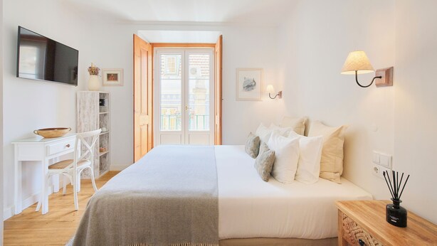 Ein Schlafzimmer mit Bett, Nachttisch, Lampe, Fernseher und Schreibtisch mit Stuhl.