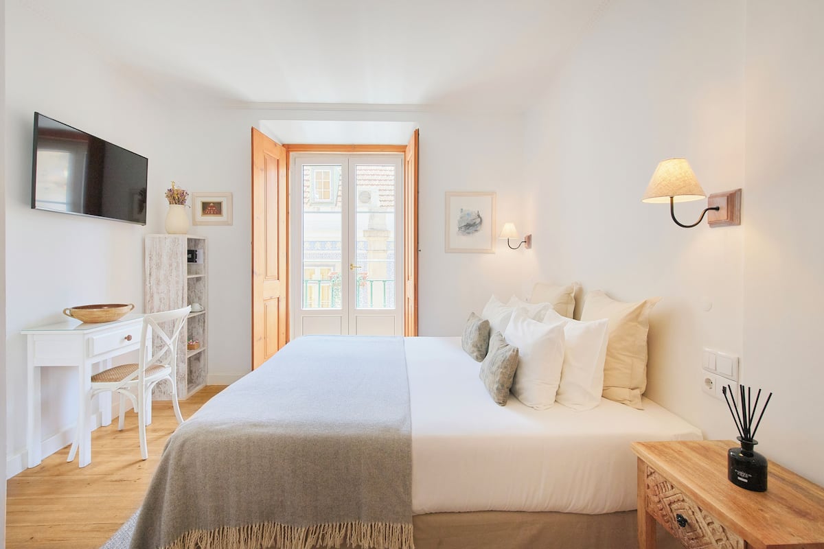 Une chambre à coucher comprenant un lit, une table de chevet, une lampe, une télévision et un bureau avec une chaise.