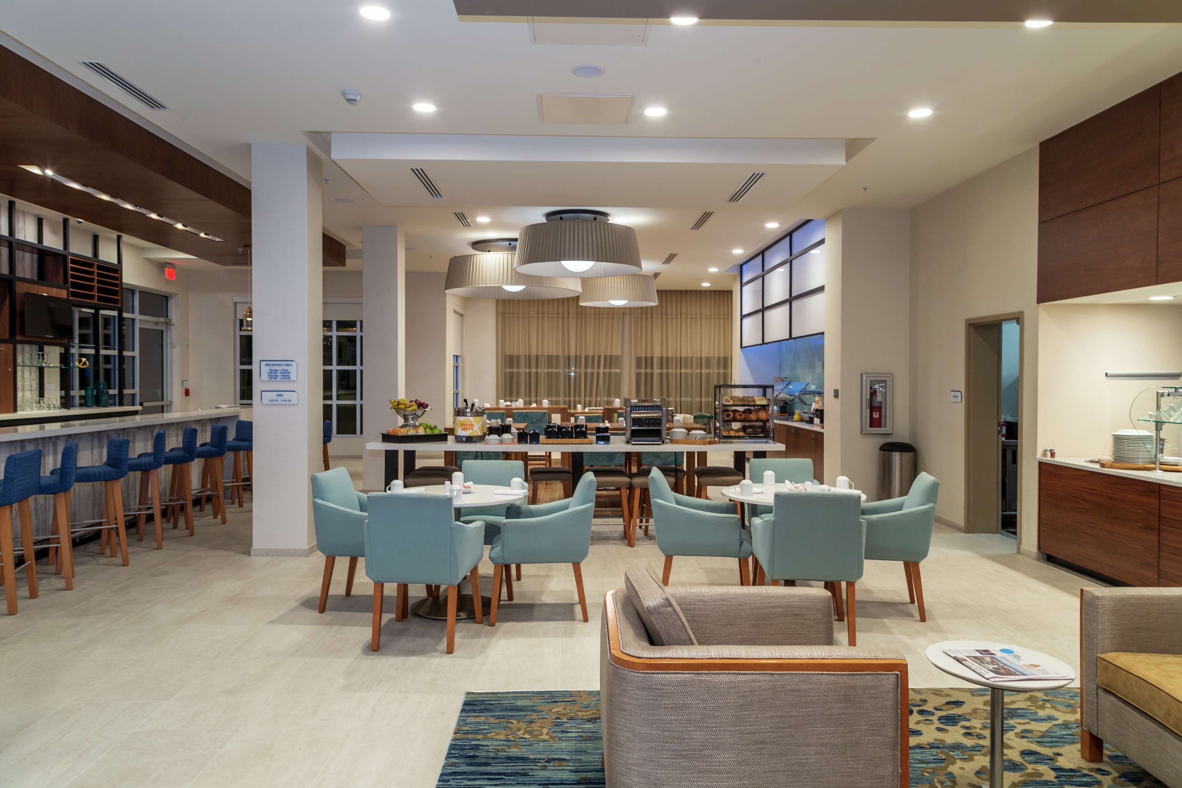 Un moderno vestíbulo de hotel con zona de bar, asientos y un espacio central para comer.