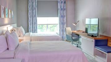 A hotel room with two beds, a desk, a chair, a TV, and a window with curtains.