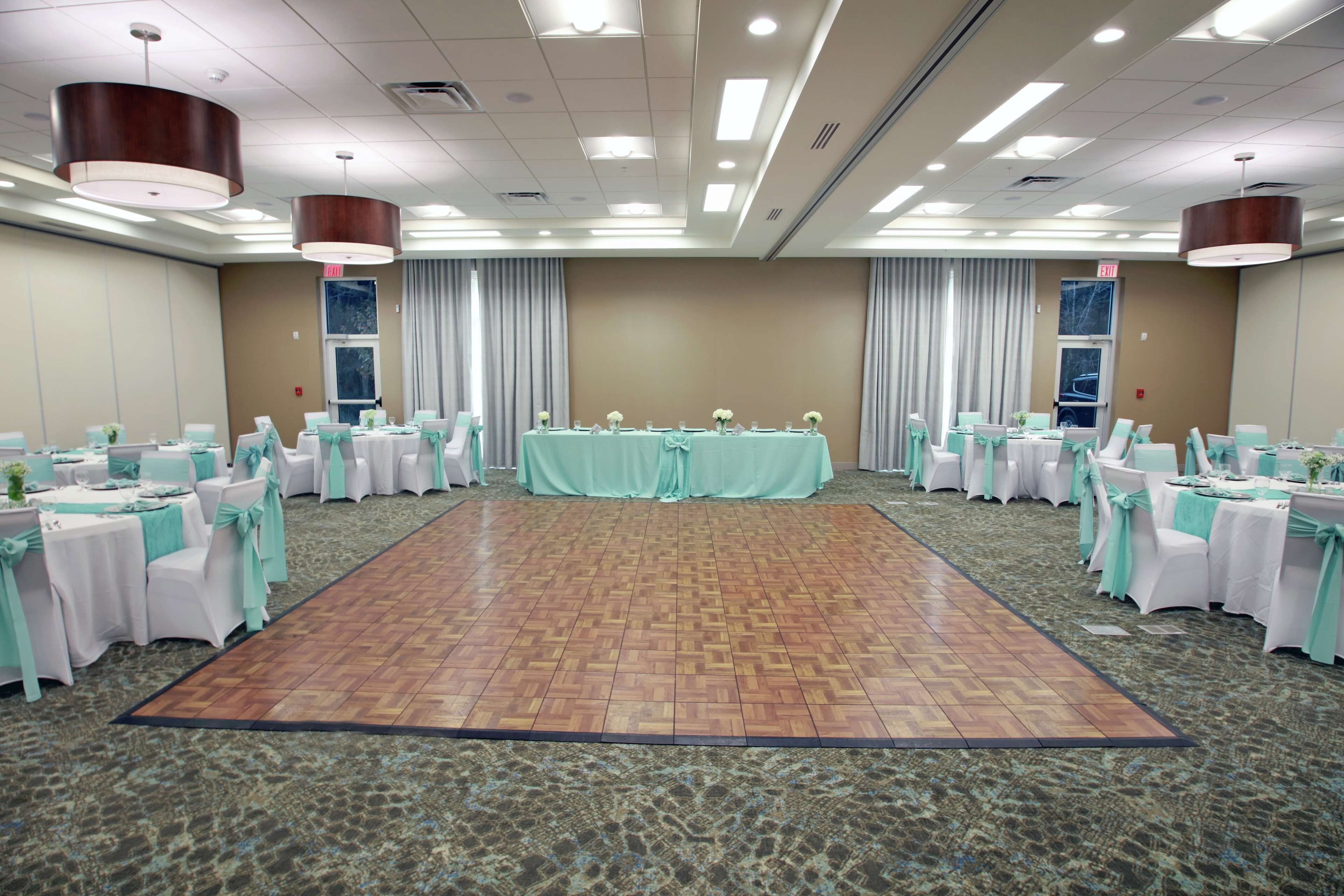 A conference room with a central stage, round tables, and chairs, all arranged for a meeting or event.