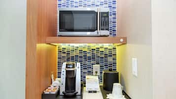 A compact kitchenette with a microwave, coffee machine, and a tea dispenser.