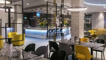Um restaurante moderno com cadeiras amarelas e pretas, um espaço de bar e chão xadrez.