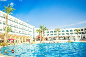 Una piscina techada, una piscina al aire libre, sombrillas