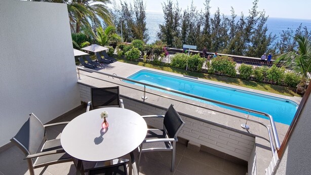 Een balkon met een zwembad, zitplaatsen buiten en uitzicht op de oceaan.