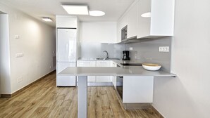 Een moderne keuken met witte kastjes, een ingebouwde oven, een koffiezetapparaat en een kom op het aanrecht.