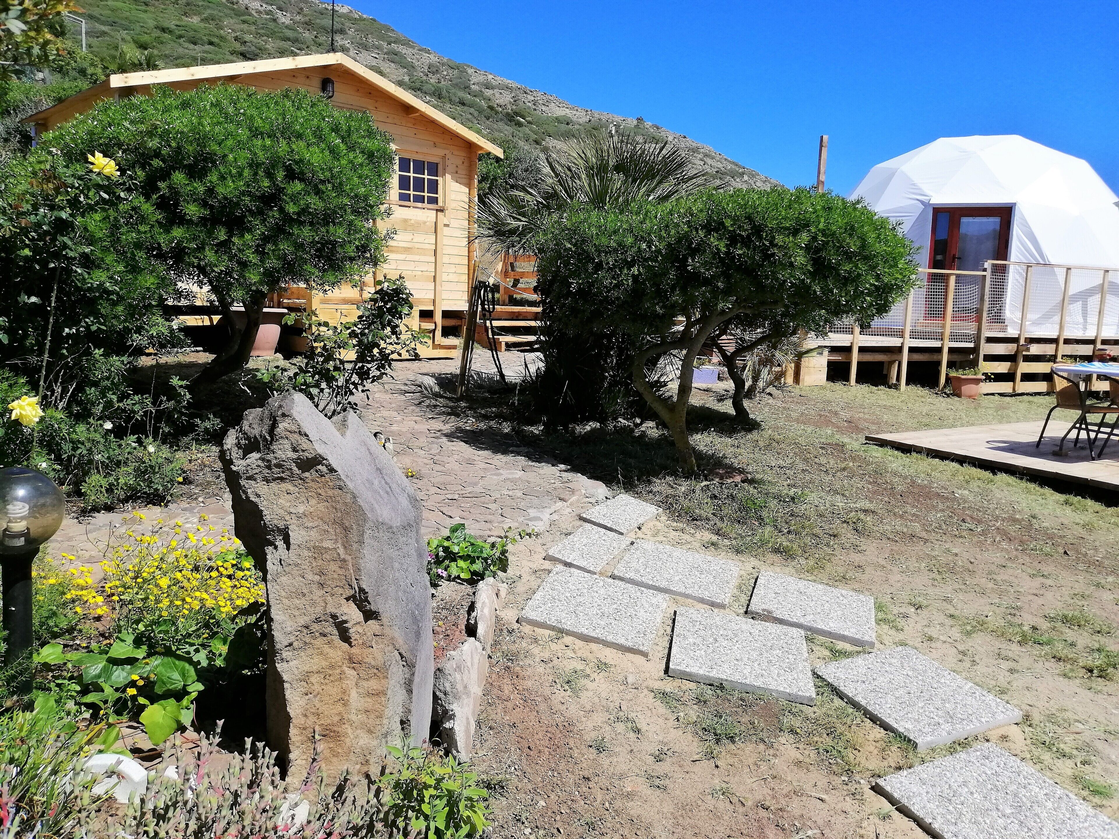 Una casa de madera rústica con un sendero de piedra que lleva a una estructura abovedada blanca.