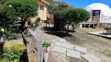 Una casa de madera rústica con un sendero de piedra que lleva a una estructura abovedada blanca.