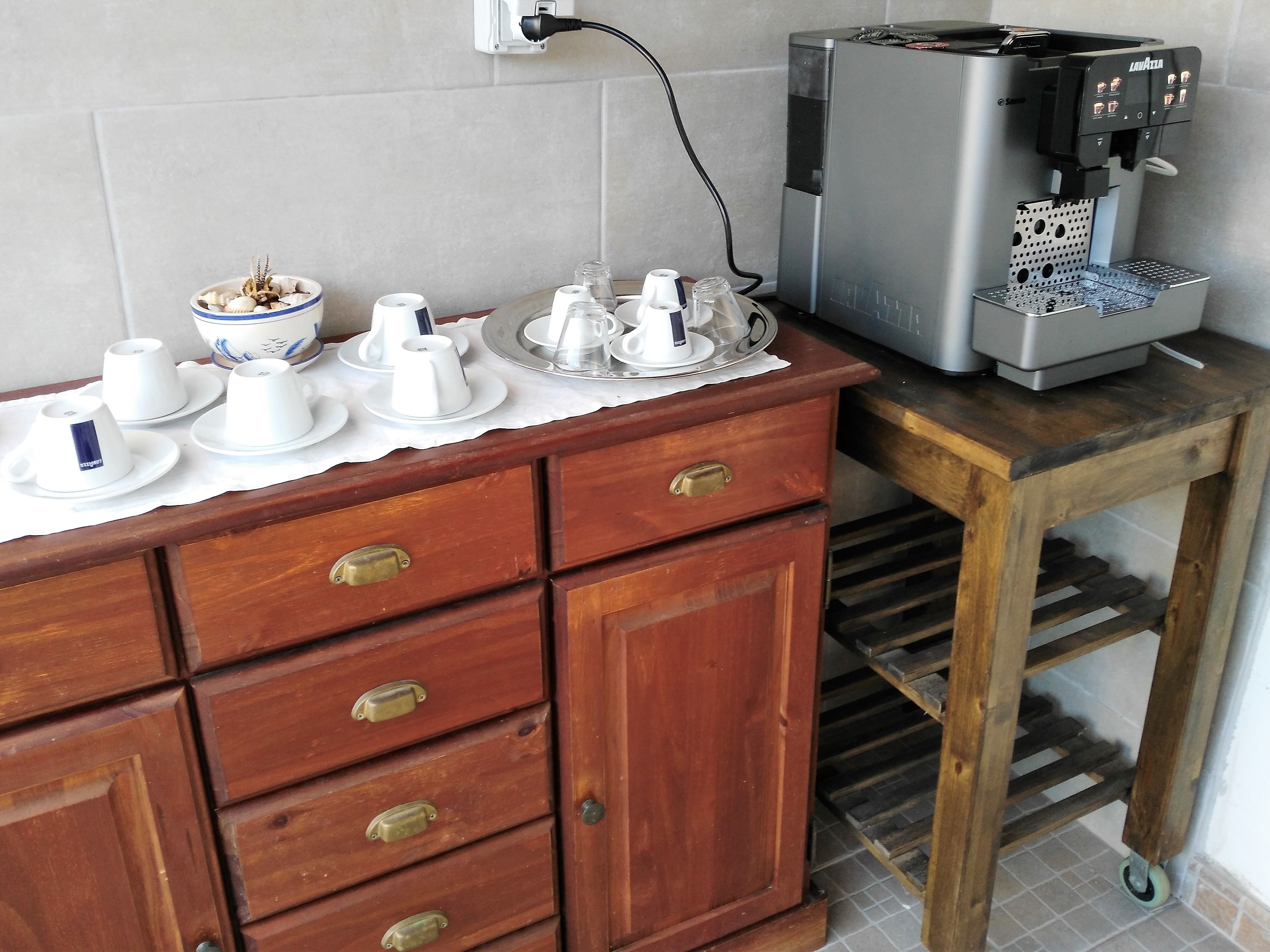 A coffee machine on a wooden table with a tiled wall in the background.