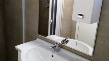 A bathroom with a white sink, a mirror, and a shower.