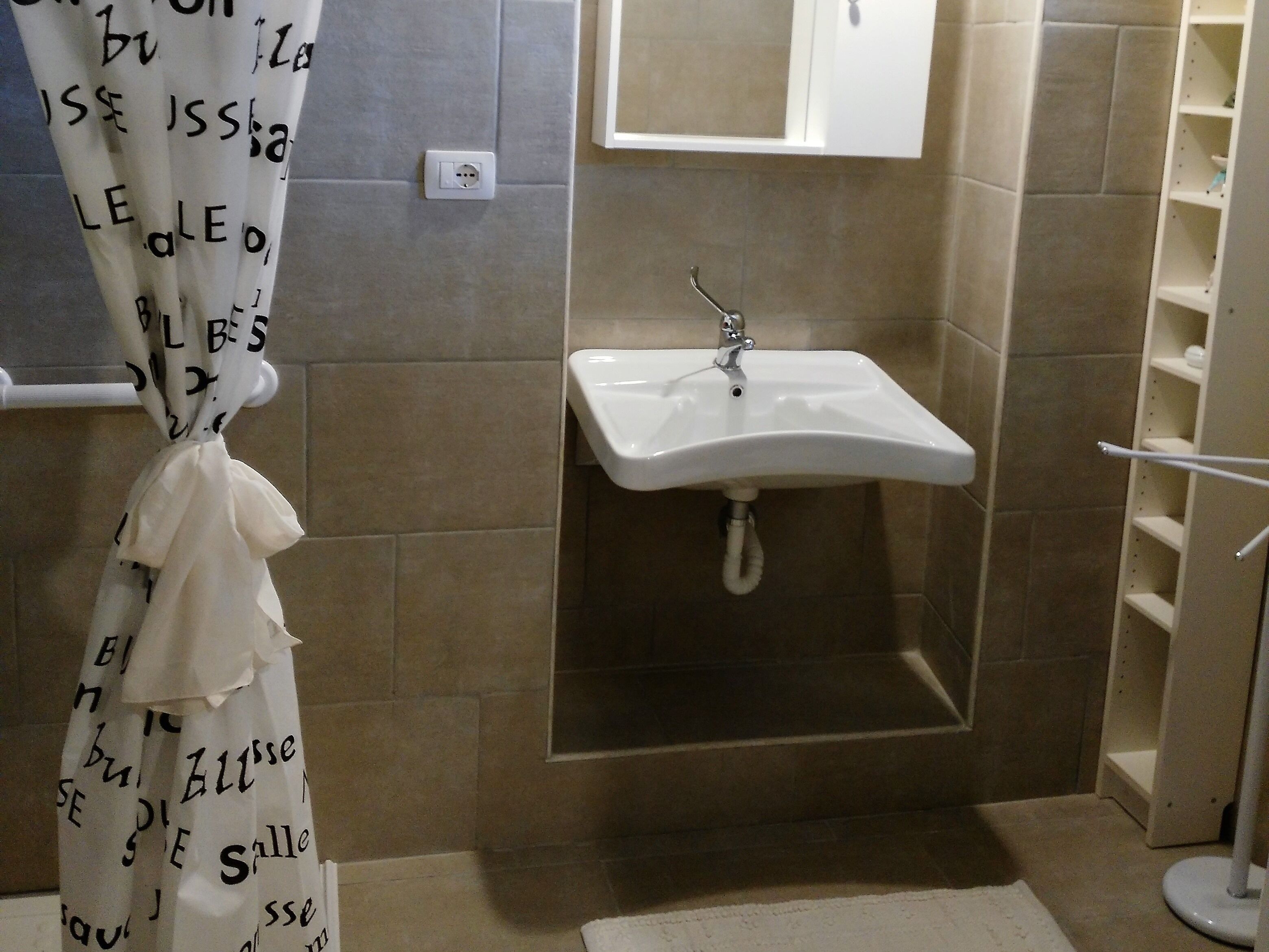 Un baño con cortina de ducha, lavamanos y espejo.