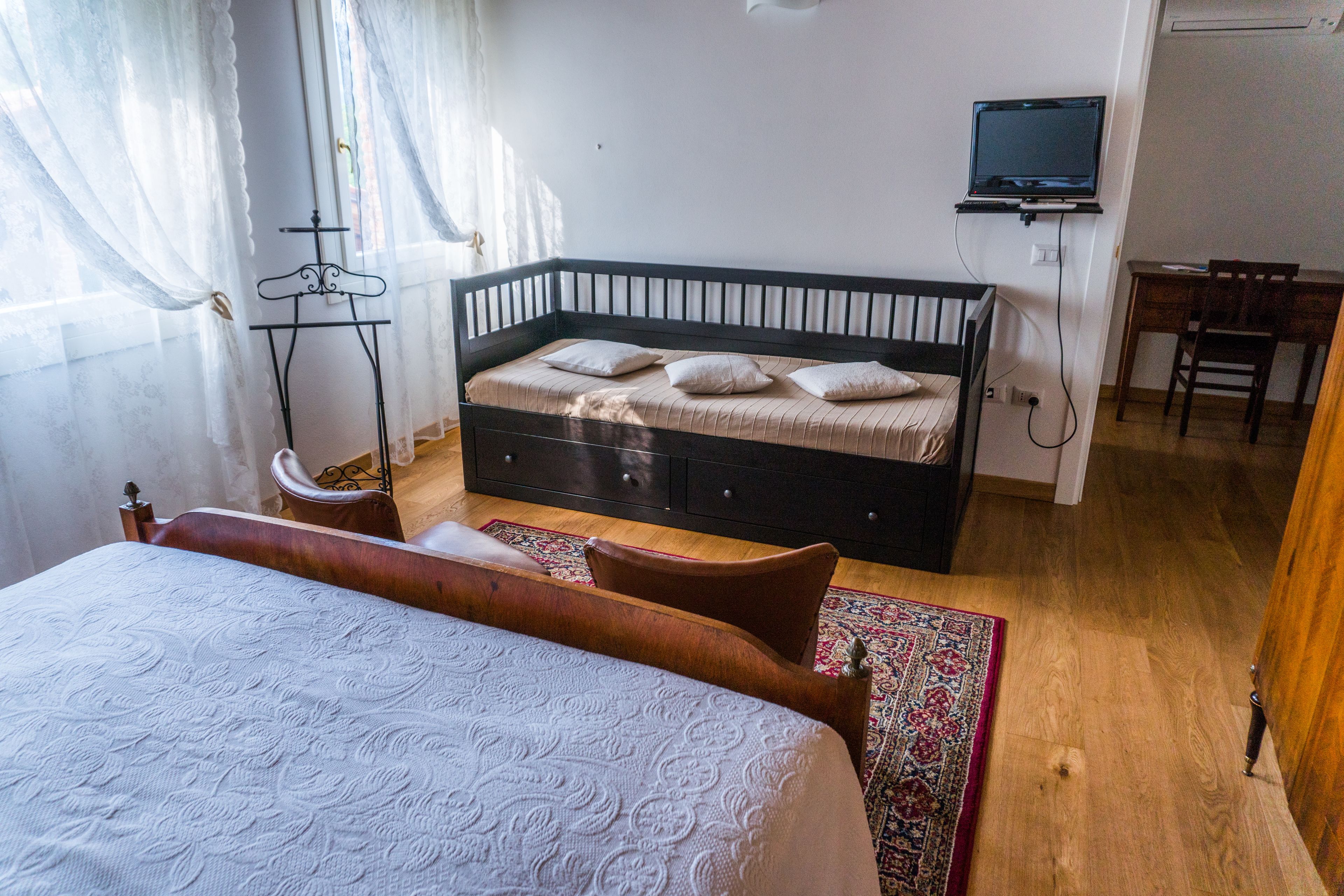 Un dormitorio con cama, escritorio, silla, televisor y armario.
