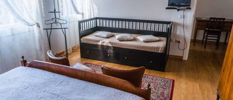 Un dormitorio con cama, escritorio, silla, televisor y armario.
