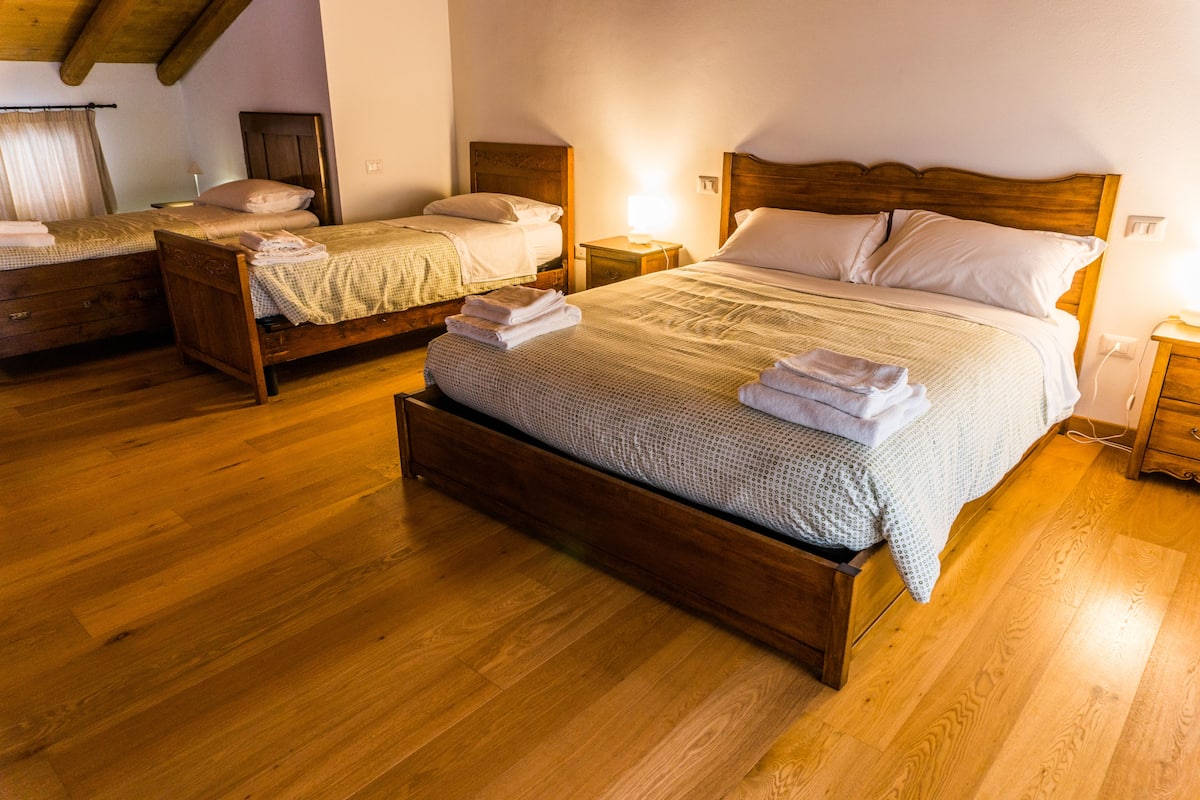 Een kamer met twee houten bedden, elk met een nachtkastje en een lamp. De vloer en het plafond zijn van hout.