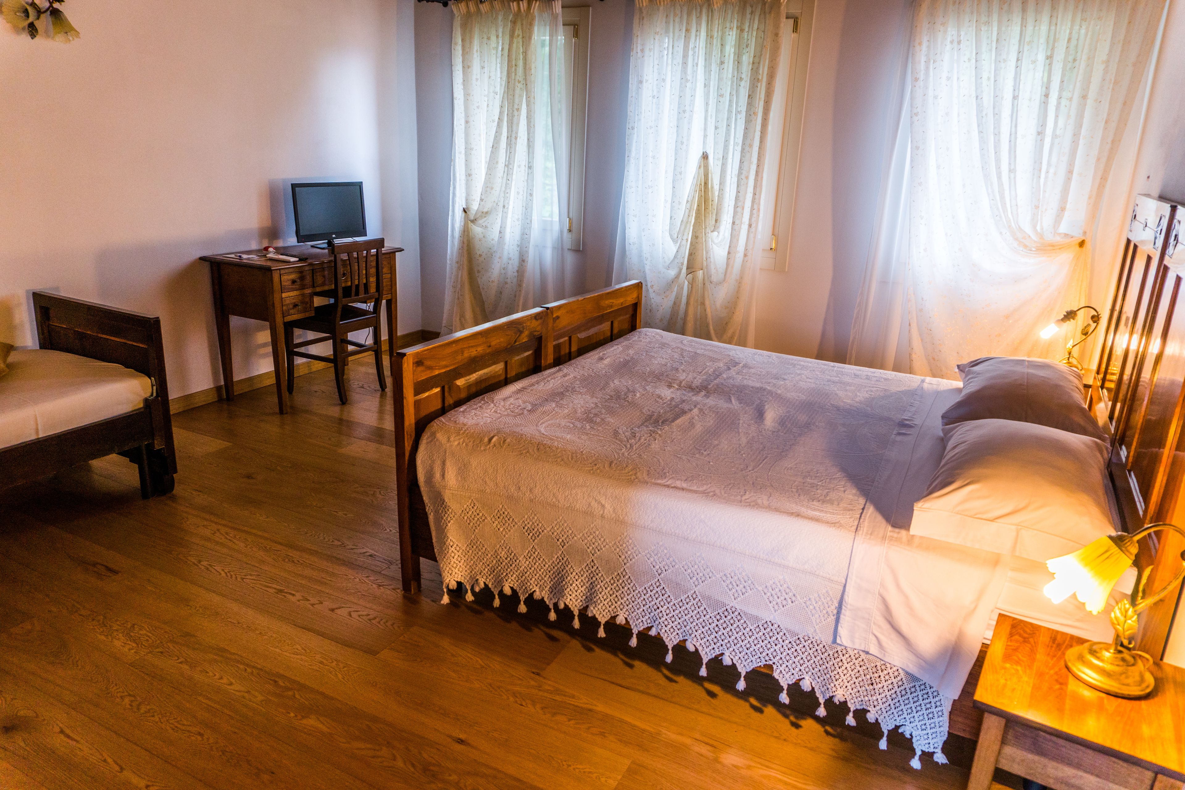 Un dormitorio con una cama de madera, un escritorio con una computadora y una lámpara.