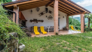 A rustic building with a covered patio, outdoor seating, and a stone wall with various items mounted on it.