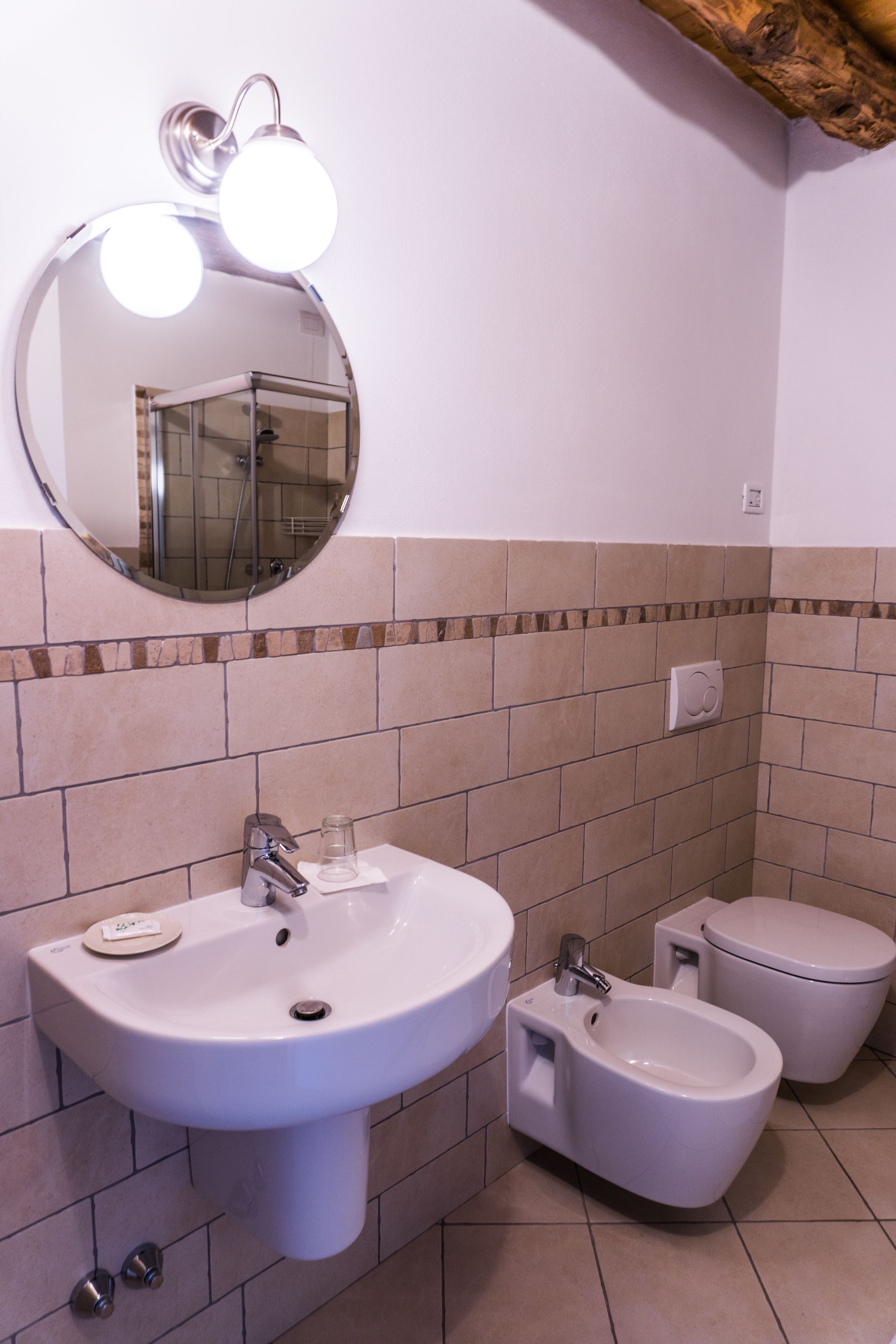 Un baño con lavamanos, bidé, inodoro y un espejo con iluminación.